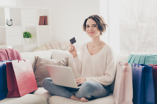 Full size photo of bob brown haired young woman hold credit card computer sit sofa buy clothes indoors inside house