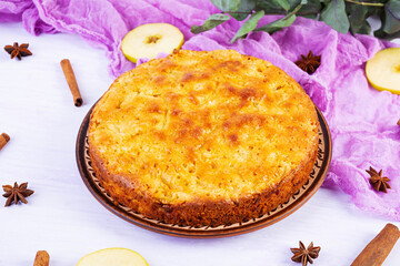 Delicious homemade apple pie on pink background. Apple pie with ingredients, apples and cinnamon