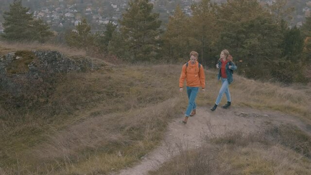 Young male and female hikers with backpack going up the mountain
