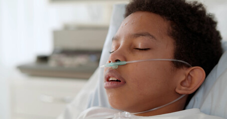 Close up of afro-american preteen boy with nasal cannula having fever and sleeping in hospital bed