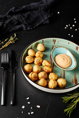 fried dumplings on a plate on a black textured background with a fork and knife