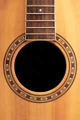 old wood guitar without strings made of light wood with brown patterns and a black hole 