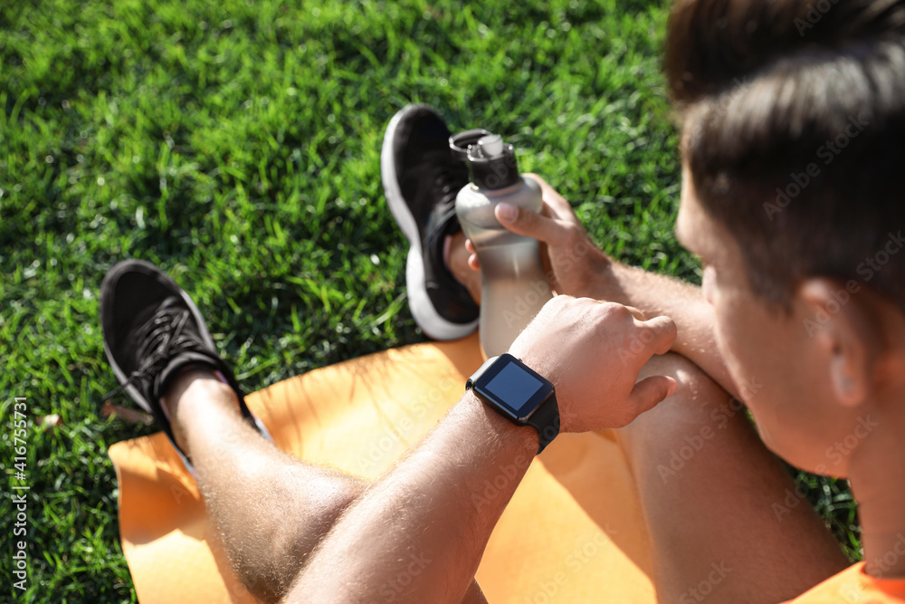 Poster Man checking fitness tracker after training in park, closeup