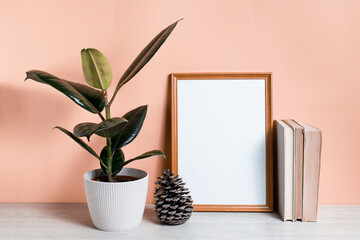 Poster with copy space. Bookshelf with Home plant ficus, books, and poster. Scandinavian-style interior. Pastel beige wall, minimalism.