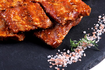 Raw marinated pork ribs on black stone plate ready for cooking. Raw bbq ribs, marinated meat for grill, meat with bone