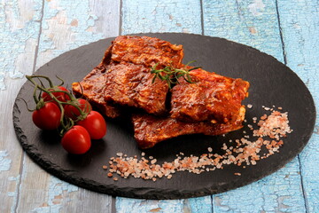 Raw marinated pork ribs on black stone plate ready for cooking. Raw bbq ribs, marinated meat for grill, meat with bone