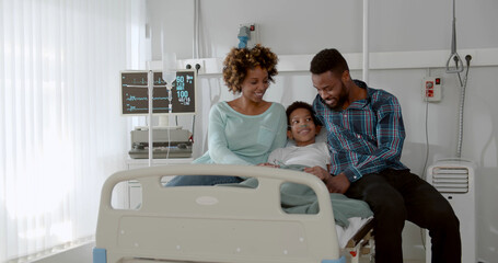 Afro-american parents visit sick son at hospital ward