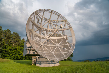 Satellite dish in a summer landscape, radiotelescope for deep space research. Ondrejov observatory, Czech republic.