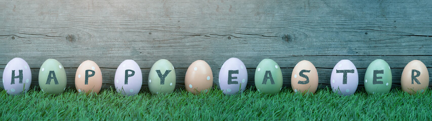 HAPPY EASTER background banner panorama greeting card - Many pastel painted dotted Easter eggs on fresh green meadow grasses and rustic wooden wood wall
