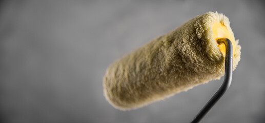 Clean fresh new paint roller for painting on gray blurred concrete background. Close up with copy empty space for text. Banner for advertising.