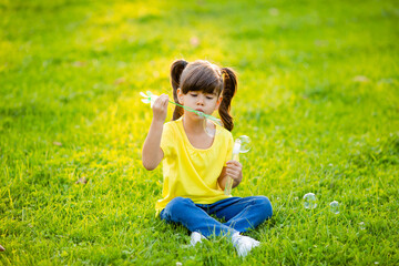 Cute little Indian girl summer on the lawn blowing soap bubbles