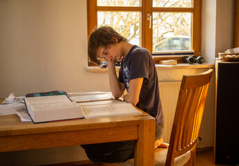 A teenaged boy in  isolation studies at home during the corona virus pandemic