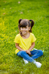 Happy little Indian girl in yellow T-shirt laughs summer on the lawn