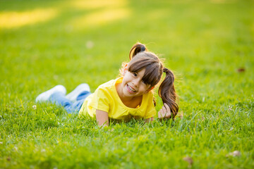 Fototapeta premium Happy little Indian girl in yellow T-shirt laughs summer on the lawn