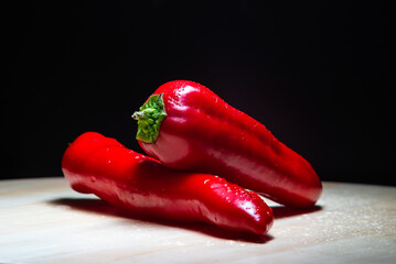red peppers lie on a wooden board on a black background
