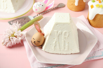 Traditional cottage cheese Easter paskha and egg with bunny ears on pink wooden table