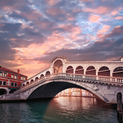 Rialto bridge on The Grand Canal in Venice, Italy in the evening on sunset. Pink purple sky with clouds.Toned square image. Famous place, romantic sights of Venice in Italy.