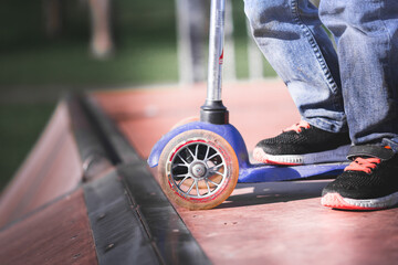 A child standing on a scooter in a skate park on a skate ramp