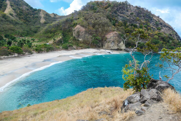 A view on idyllic Koka Beach from a nearby headland. Hidden gem of Flores, Indonesia. Beach is gently washed by waves. Serenity and calmness. Island life. Beach surrounded by mountains.