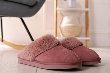 Pink warm slippers on floor in room