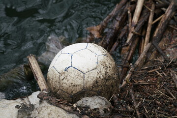 Fußball in einem Fluss in Form von Treibgut und Umweltverschmutzung