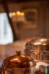 Old copper casserole with lid and brass handles in copper flower pot on a normal background. Food photography props. High quality photo