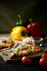 Homemade Meat and Cheese thin crust Pizza on wood table with ingredients.