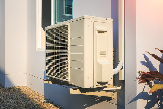 Condenser Unit Or Compressor Outside Home Or Residential Building. Unit Of Central Air Conditioner (AC) Or Heating Ventilation Air Conditioning System (HVAC). Electric Fan And Refrigerant Pump Inside.