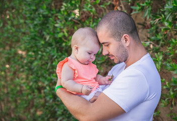 father and daughter leaned their heads to each other on the background of a hedge