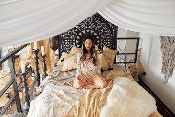 Mature beautiful dark haired woman in shamanic ethnic outfit in bali style decorated room