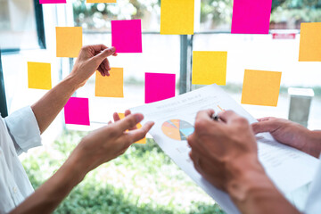 Young creative team professional using post it notes in glass wall to writing strategy business...