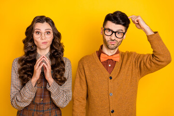 Portrait of attractive nervous confused couple thinking expecting news isolated over bright yellow...