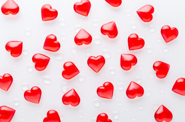 Fototapeta na wymiar white background with red hearts pattern and water drops, flat lay