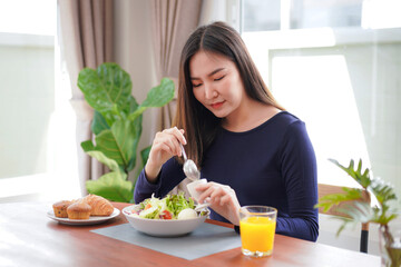 Obraz na płótnie Canvas Young asian woman eating healthy salad with fresh vegetable and orange juice on wellness lifestyle