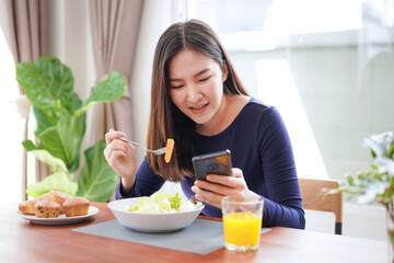 Obraz na płótnie Canvas Young asian woman eating healthy salad with fresh vegetable and dip the carrots with a fork