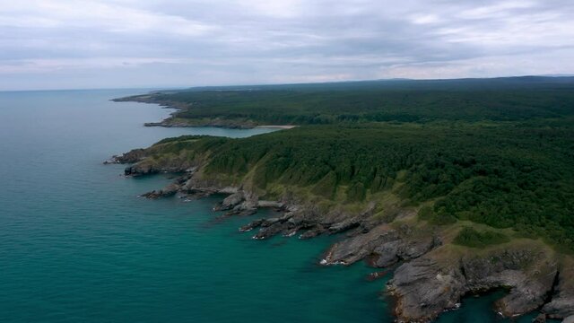 Drone flight above a picturesque rocky coastline with small wild beaches and green forests on the southern coast of the Black Sea, Bulgaria