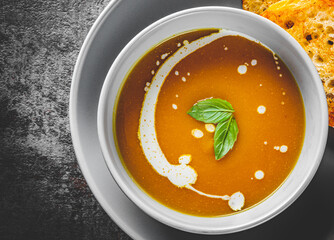 Pumpkin soup in bowl on Dark grey black slate background