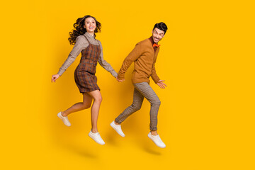 Fototapeta na wymiar Full length profile side photo of young couple jump walk empty space good mood isolated on yellow color background
