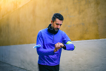 Close up of male hands using fitness app on smart watch. Man resting after jogging reading run...