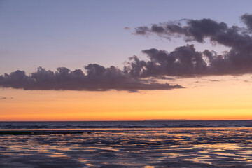 Westward Ho beach in North Devon around sunset. the tide is out exposing patterns in the sand and small pools of water