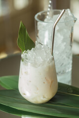 
stylish cold drink with ice on bamboo leaves with metal straw aesthetic photography food styling
