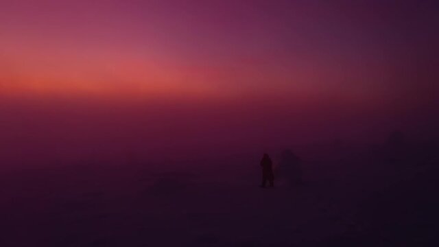 Aerial view of Person with a lantern on a foggy fell, sunset - descending, drone shot