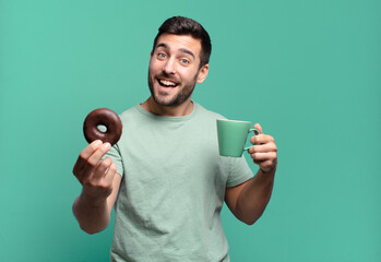young handsome blond man with a chocolate donut and a coffee cup. breakfast concept