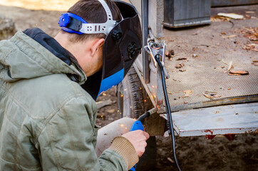 welder works at home in a protective mask without gloves