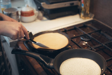 russian woman cooks pancakes in a frying pan