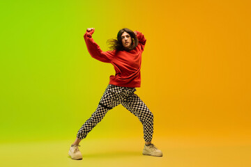 Freedom. Stylish sportive girl dancing hip-hop in stylish clothes on colorful background at dance hall in neon light. Youth culture, movement, style and fashion, action. Fashionable bright portrait.