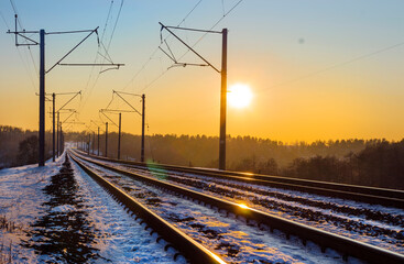 Fototapeta na wymiar Footsteps along the railway tracks in winter at sunset