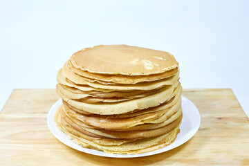 a stack of Russian pancakes on a white background on a wooden board, pancakes on Shrovetide before...