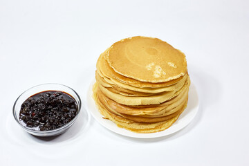 a stack of Russian pancakes and a bowl of cherry jam on a white background, pancakes on Shrovetide before Lent