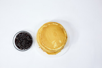 a stack of Russian pancakes and a bowl of cherry jam on a white background, pancakes on Shrovetide before Lent